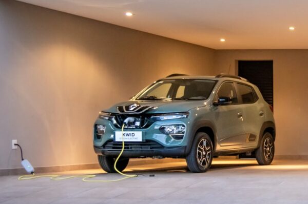 Renault Kwid elétrico na cor verde está conectado a uma tomada comum na garagem