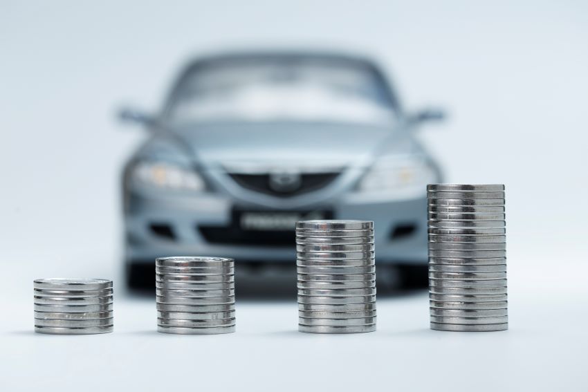 Imagem mostra pilhas de moedas perfiladas com carro ao fundo