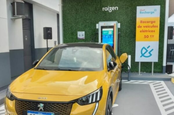 Carro elétrico amarelo faz recarga em eletroposto