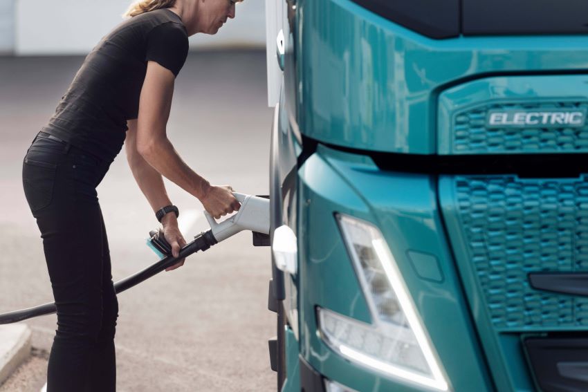 Mulher conecta equipamento de recarga em caminhão Volvo FM Electric