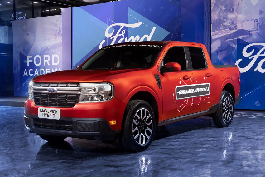 Picape vermelha estacionada em frente a painéis azuis com a marca Ford ao fundo