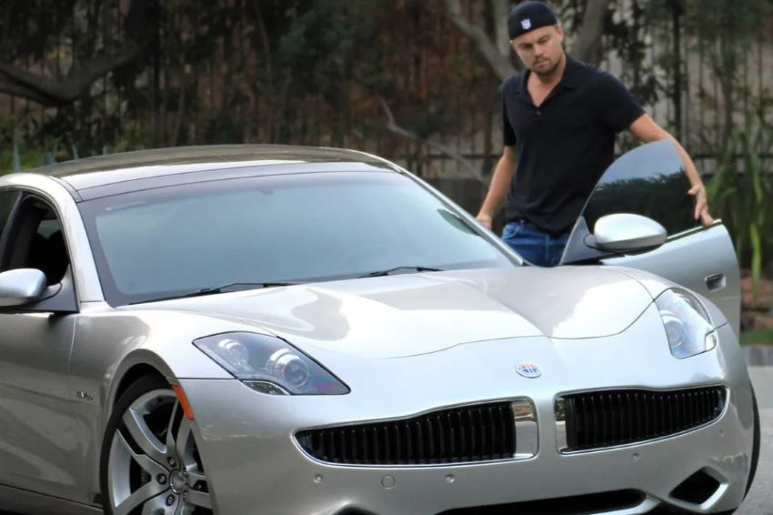De boné, ator Leonardo DiCaprio observa de perto seu carro Fisker Karma