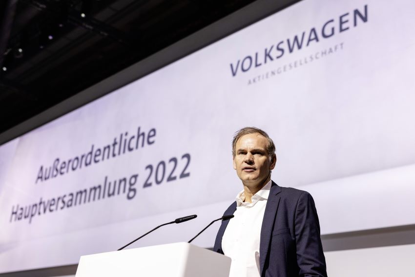 Oliver Blume, vestindo um blazer, discursa em frente a painel com o nome Volkswagen