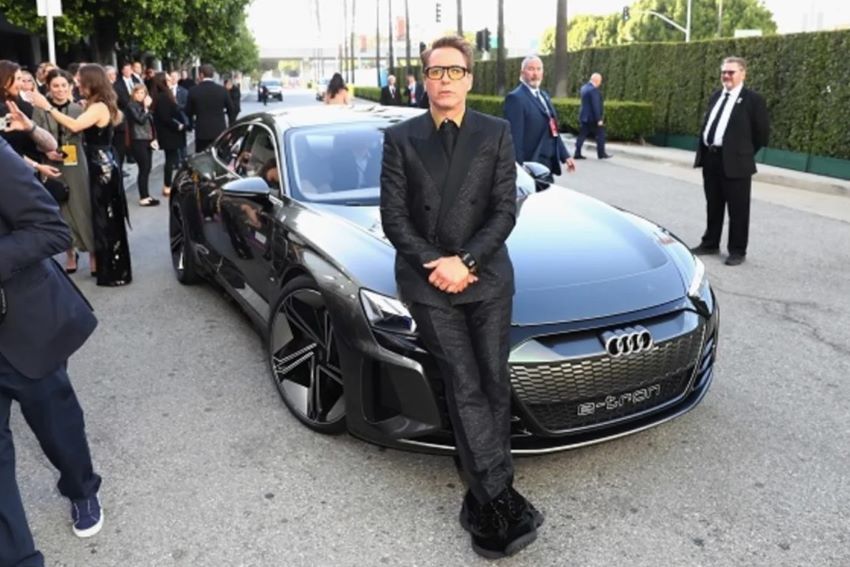 Robert Downey Jr. está apoiado no capô do carro Audi e-tron GT