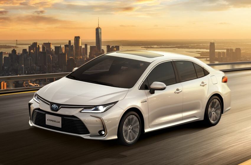 Toyota Corolla Altis branco é visto em rodovia com cidade ao fundo