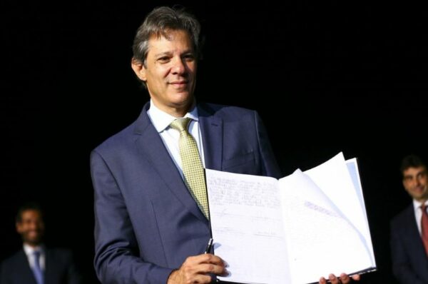 Ministro Fernando Haddad mostra livro com sua assinatura