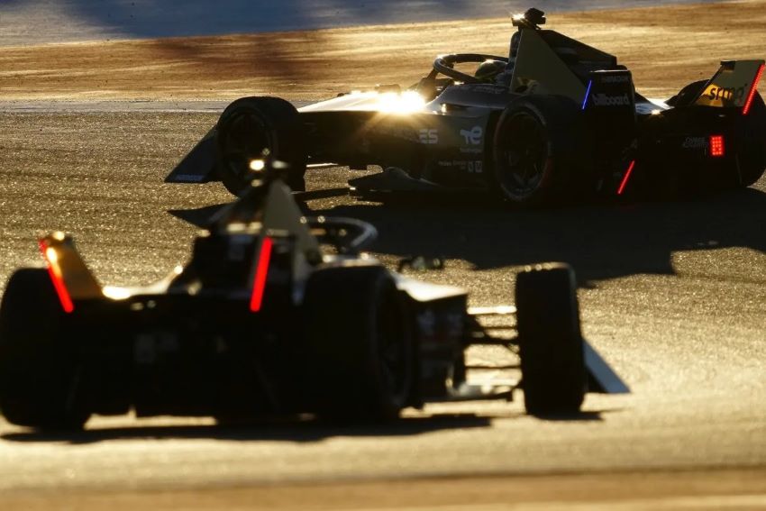 Dois carros da Fórmula E são vistos pela traseira fazendo curva para a esquerda em circuito