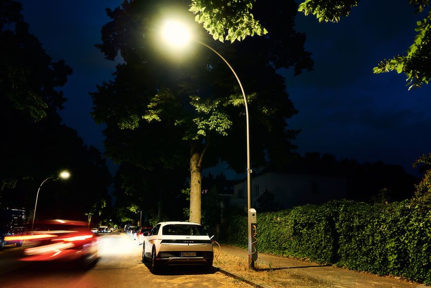 Carro elétrico está ligado à poste de luz em período noturno