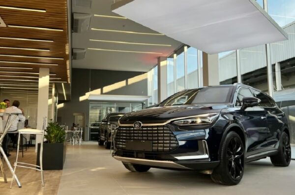 Carro elétrico preto dentro de salão de concessionária é destacado na imagem