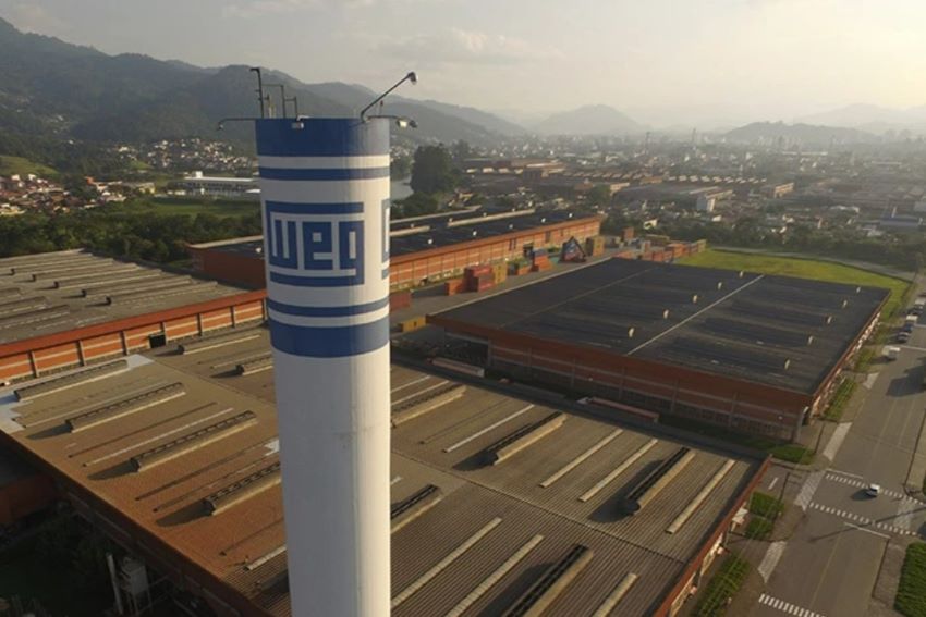 Visão aérea da fábrica mostra torre de caixa d'água branco com logotipo da WEG azul em primeiro plano