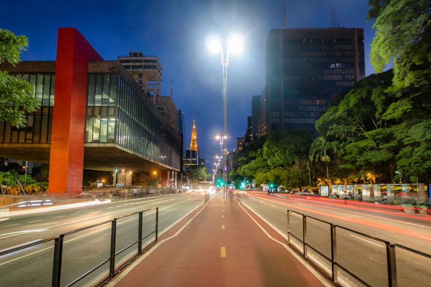 Imagem mostra movimento de veículos na Avenida Paulista, durante a noite.