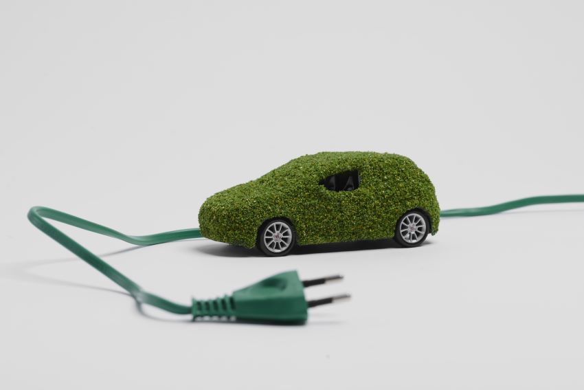 Imagem conceitual mostra carro de brinquedo coberto de folhas com fio de tomada à sua volta, em um fundo branco