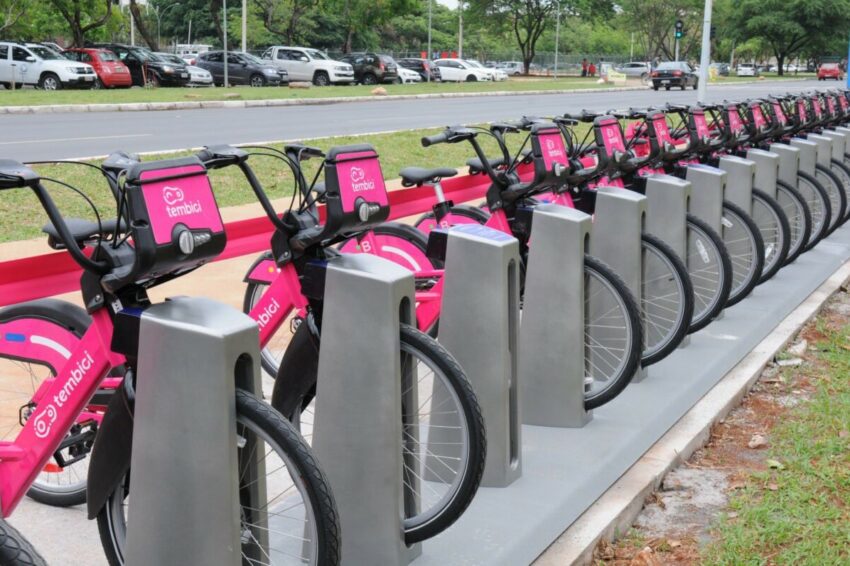 Bicicletas na cor rosa estão paradas em estação no meio da cidade