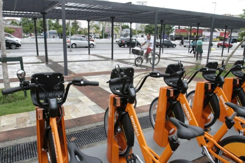 Bicicletas na cor laranja estão travadas em estação na cidade