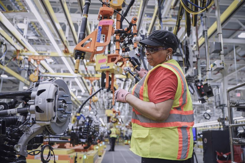 Usando equipamentos de proteção individual, mulher trabalha em linha de montagem de fábrica da Ford nos Estados Unidos