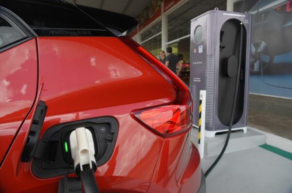 Imagem mostra carro elétrico vermelho conectado a eletroposto