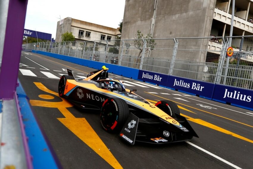 Carro laranja e preto da McLaren passa próximo a muro de proteção de circuito