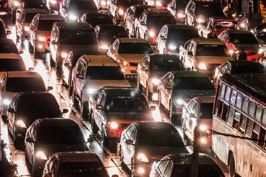 Imagem mostra tráfego intenso de veículos em avenida de uma grande cidade no período noturno