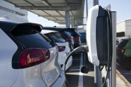 Imagem mostra carros estacionados em frente a um carregador para veículos elétricos