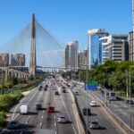 Carros trafegam por avenida movimentada de São Paulo, com a Ponte Octávio Frias ao fundo