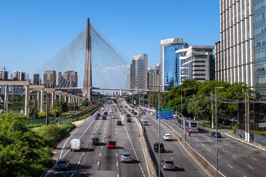 Carros trafegam por avenida movimentada de São Paulo, com a Ponte Octávio Frias ao fundo