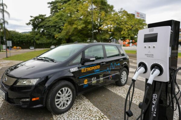 Carro elétrico preto estacionado ao lado de estação de recarga