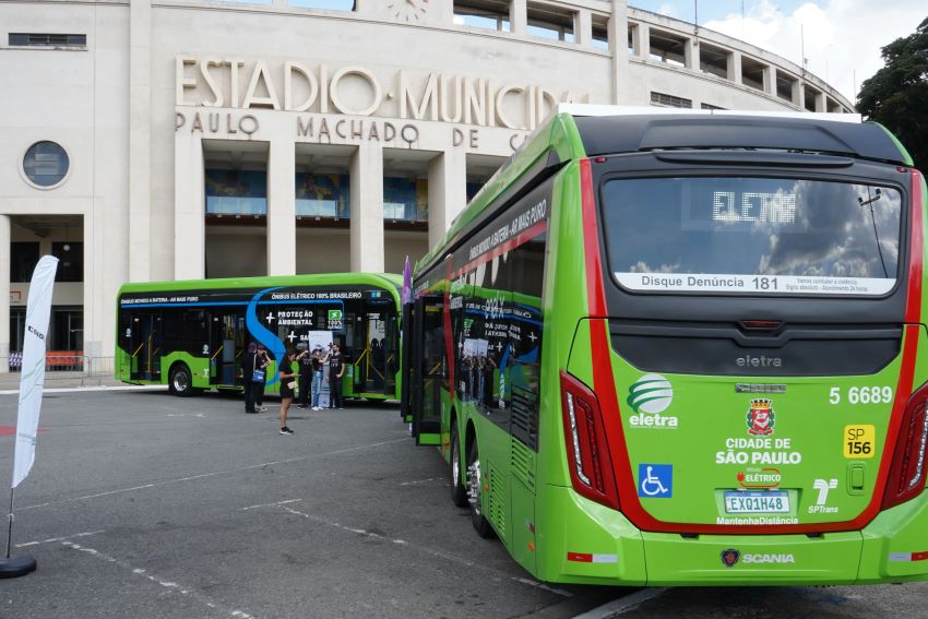 Dois ônibus elétricos verdes estão estacionados em frente à fachada do estádio do Pacaembu