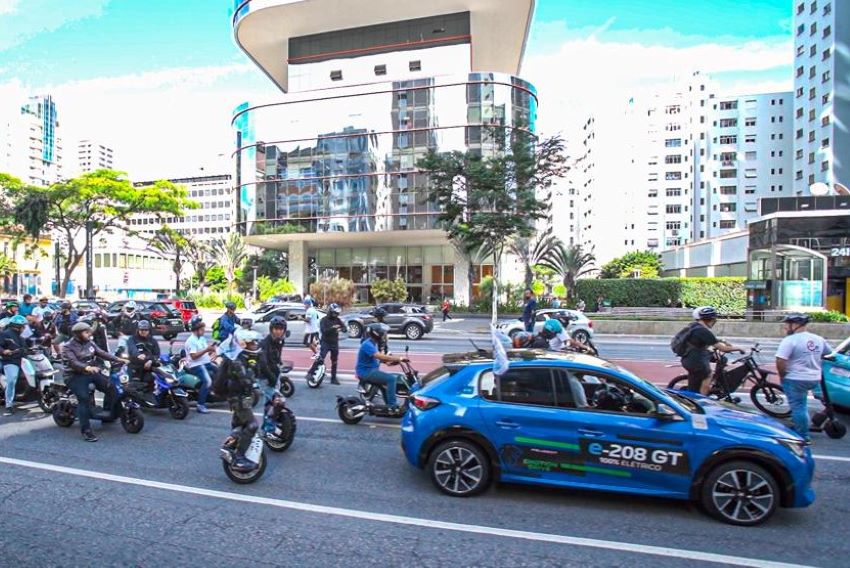 Carreata no Dia da Mobilidade Elétrica, com um carro azul acompanhado de motos e bicicletas elétricas