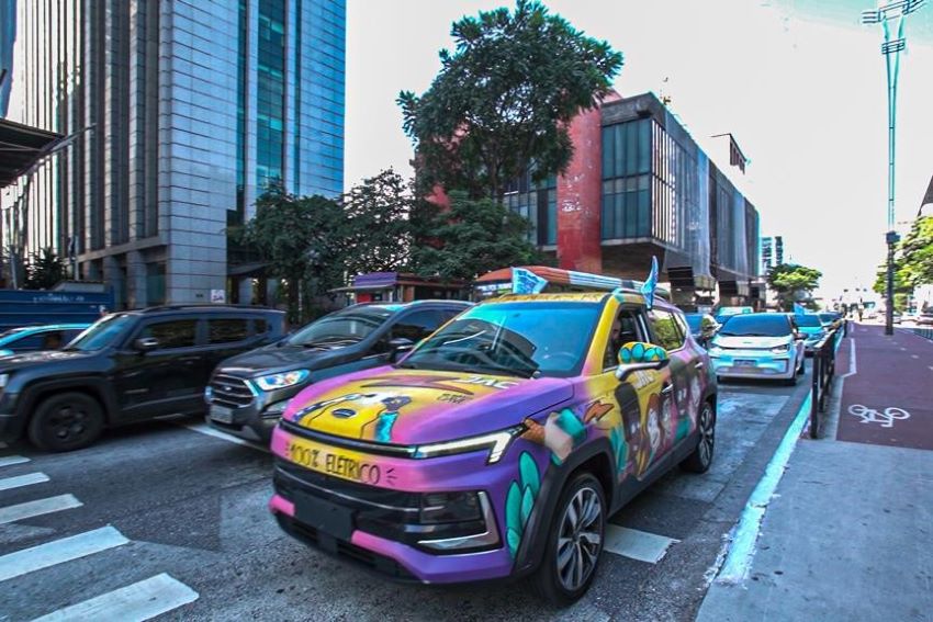 Carro colorido com os dizeres "100% elétrico" no capô é visto em carreata pelas ruas de São Paulo