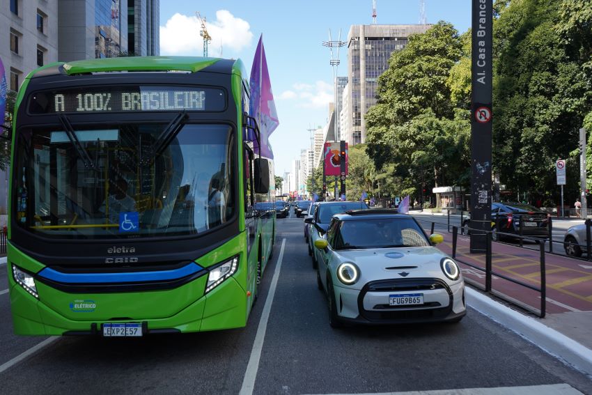 Ônibus elétrico verde está ao lado de carro elétrico branco na Avenida Paulista