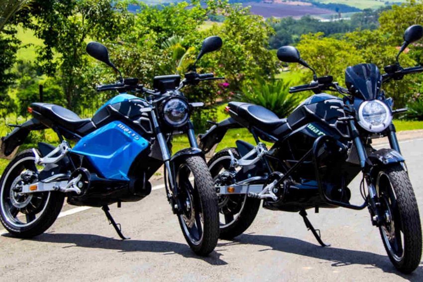 Duas motos elétricas, uma preta e uma azul, estacionadas