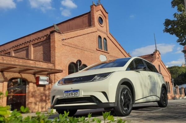 BYD Dolphin na cor branca está estacionado em frente a prédio de tijolos à vista