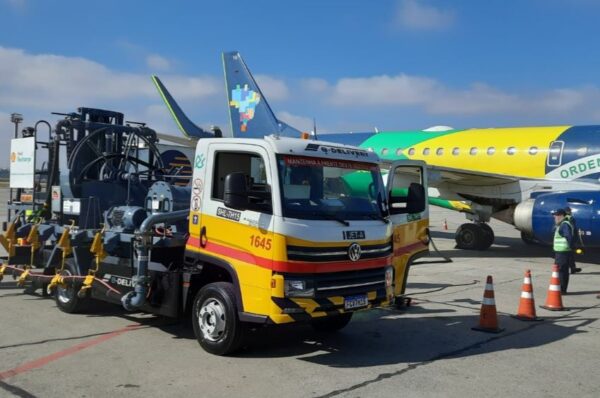 Caminhão elétrico está ao lado de avião na pista do aeroporto