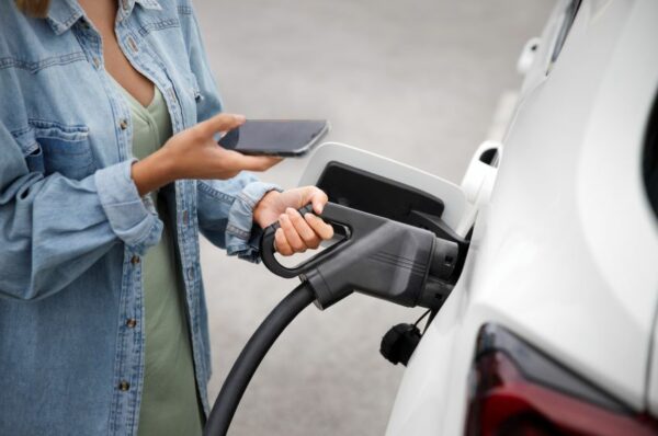 Pessoa carregando seu carro elétrico com o auxílio do celular