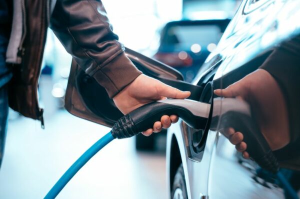 Homem conecta plugue em carro elétrico