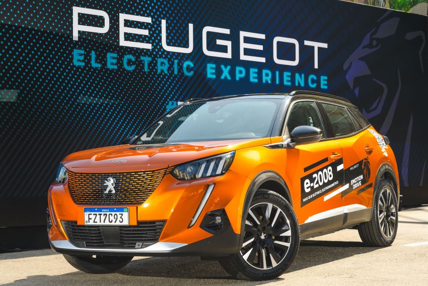 Peugeot e-2008 está estacionado em frente a letreiro com os dizeres Electric Experience