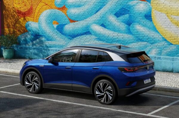 Carro azul estacionado em frente a parede com grafite