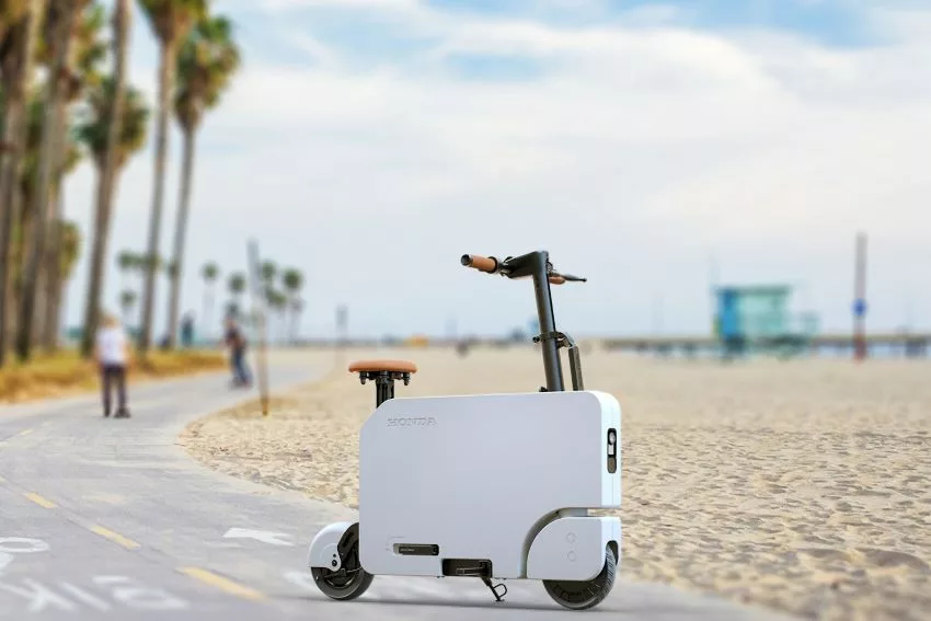 Modelo compacto de scooter elétrica da Honda na cor branca, em ciclovia na praia