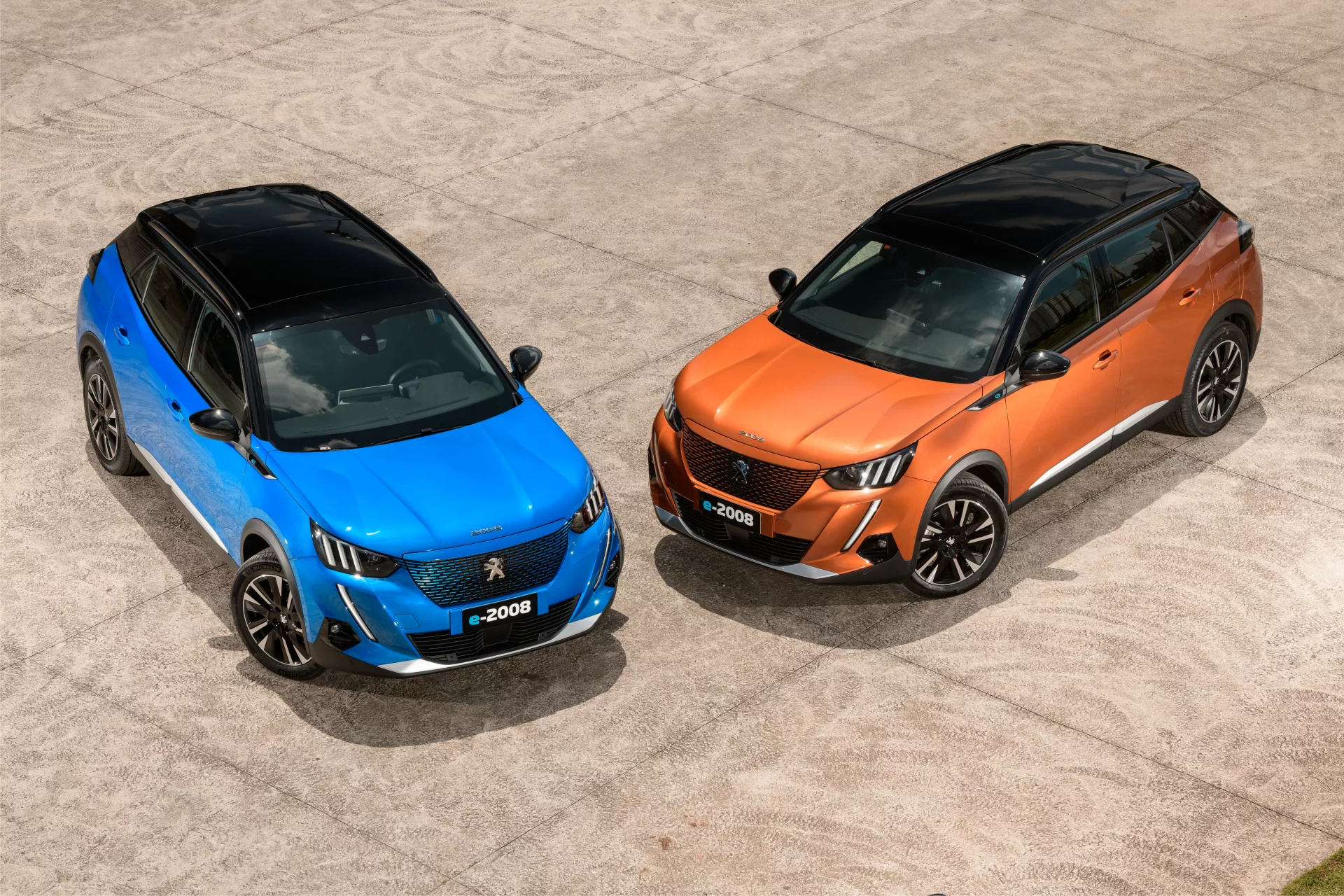 Dois carros elétricos da Peugeot, o modelo e-2008, nas cores azul e laranja
