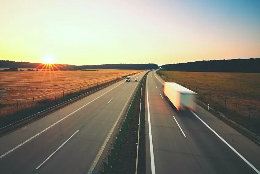 Imagem mostra veículos trafegando em rodovia ao nascer do sol