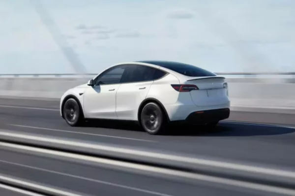 Tesla Model Y branco é visto circulando sobre ponte em cenário urbano