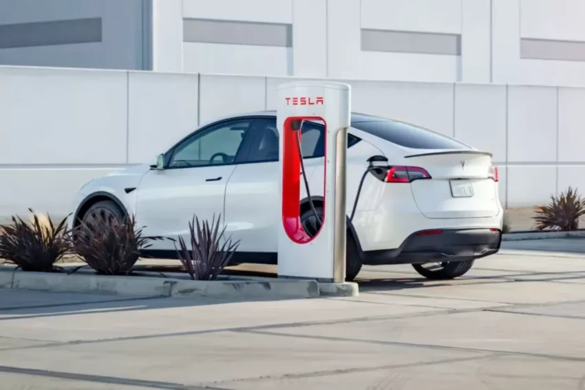 Tesla Model Y branco recebe recarga em estacionamento