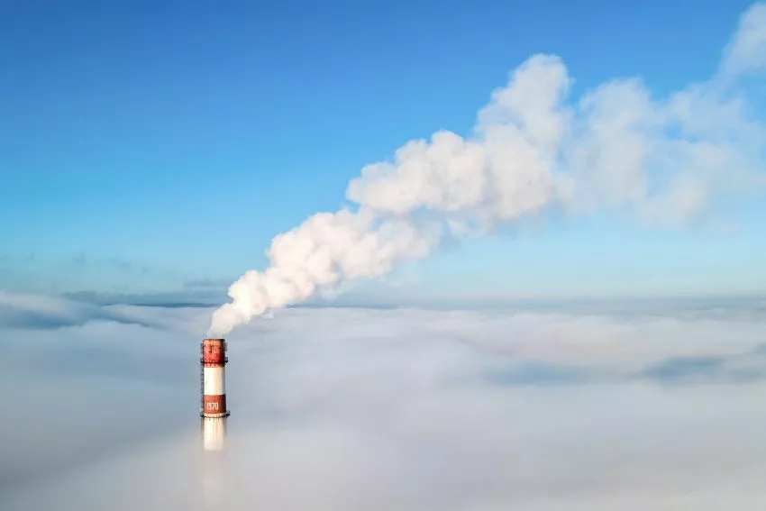 Imagem aérea mostra fumaçã saindo de chaminé acima do nível das nuvens