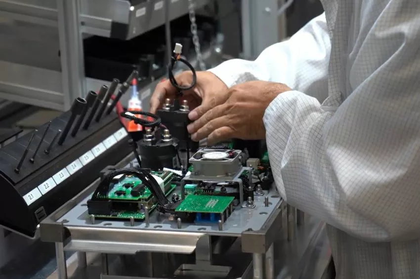 Imagem mostra mãos de homem montando componente eletrônico