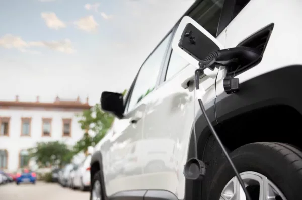 Carro elétrico branco recebe recarga