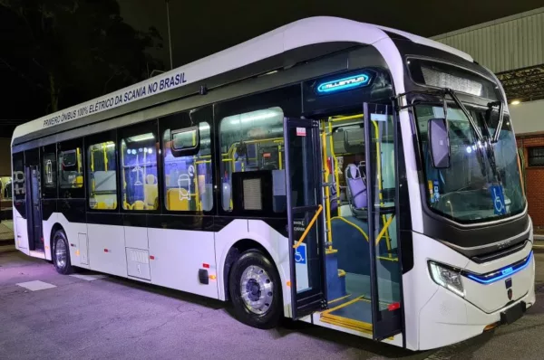 Ônibus elétrico da Scania todo pintado de branco estacionado em pátio durante a noite