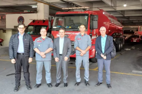 Representantes dos bombeiros e da ABVE posam para foto em frente a caminhão de bombeiros