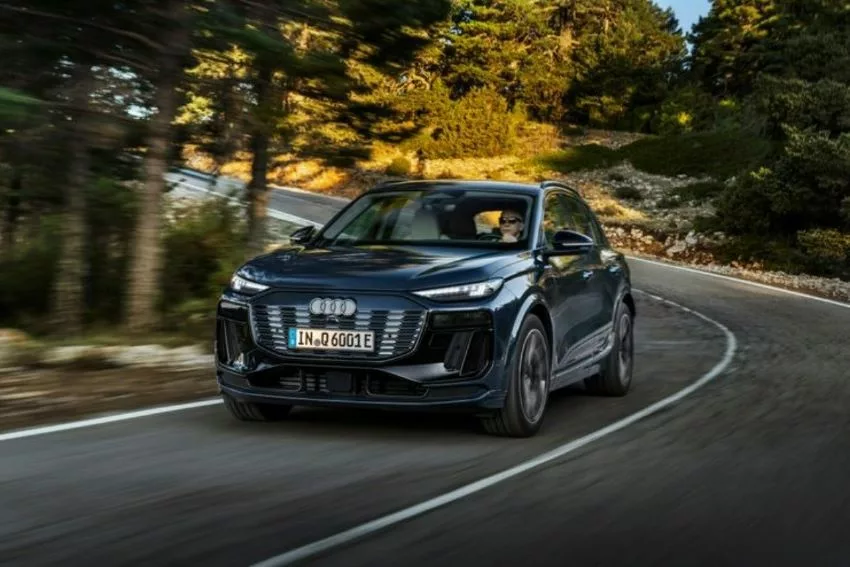 Audi Q6 e-tron visto de frente, em estrada rodeada por árvores