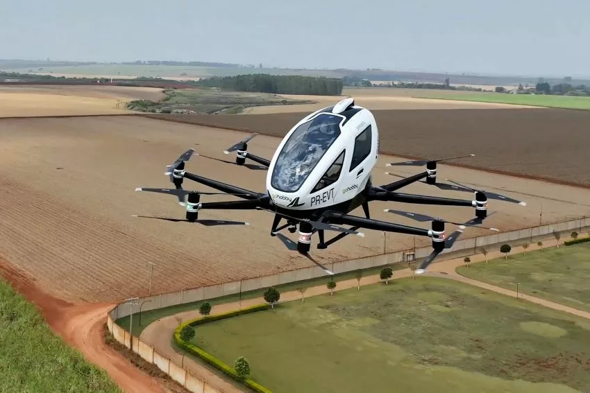 Imagem mostra eVTOL (veículo aéreo de decolagem e aterrissagem vertical) voando sobre área verde