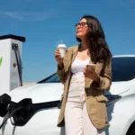 mulher bebendo café ao lado de um carro